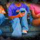 Three individuals sitting on steps, all engrossed in using their smartphones. The background appears blurry, with a dark and starry effect framing the scene.