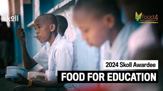 Three children are eating from bowls while seated against a wall. Text on the image reads: "2024 Skoll Awardee: Food for Education.