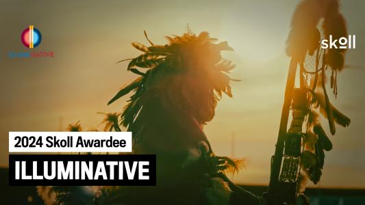 A silhouette of a person wearing a feathered headdress against a sunset background. Text on the image reads "2024 Skoll Awardee, IllumiNative" with the Skoll and IllumiNative logos.