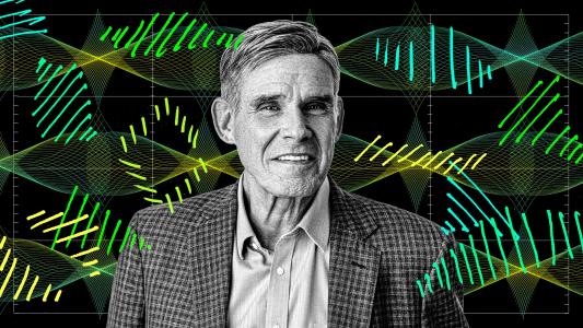 A man in a checked jacket and collared shirt stands in front of a digital background featuring stylized DNA strands and data graphs.