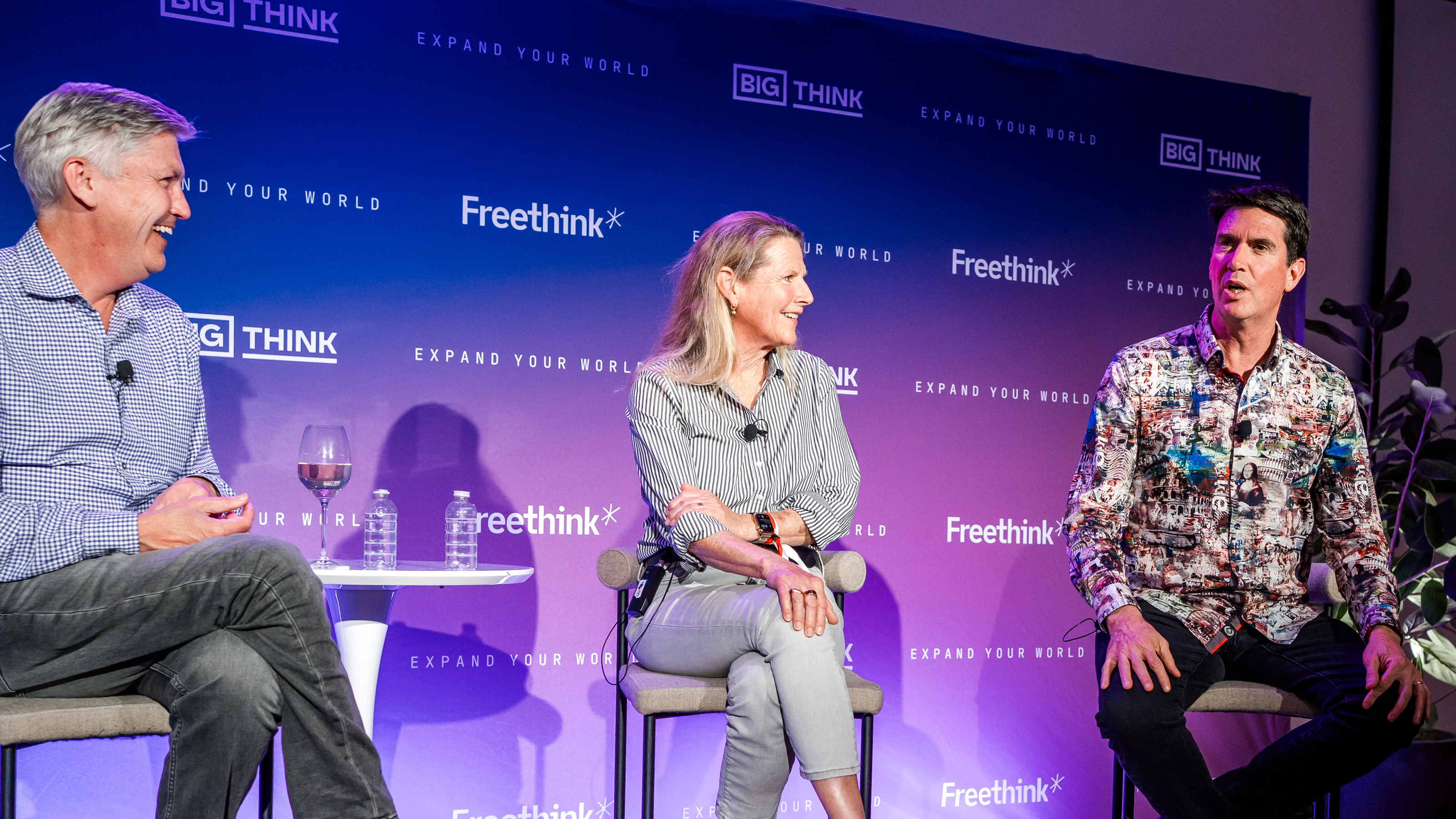 Three people sit on stage having a discussion, with two men and one woman, in front of a backdrop with "Big Think" and "Freethink" logos.