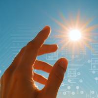 A hand reaches toward the sun against a blue sky, with faint digital circuit patterns overlaid in the background.