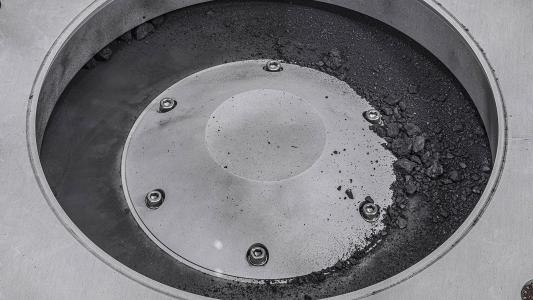 A close up of a metal container with bits of the Bennu asteroid sample on it