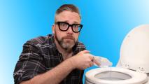 A man with glasses pours liquid from a plastic bag into a toilet against a blue background.
