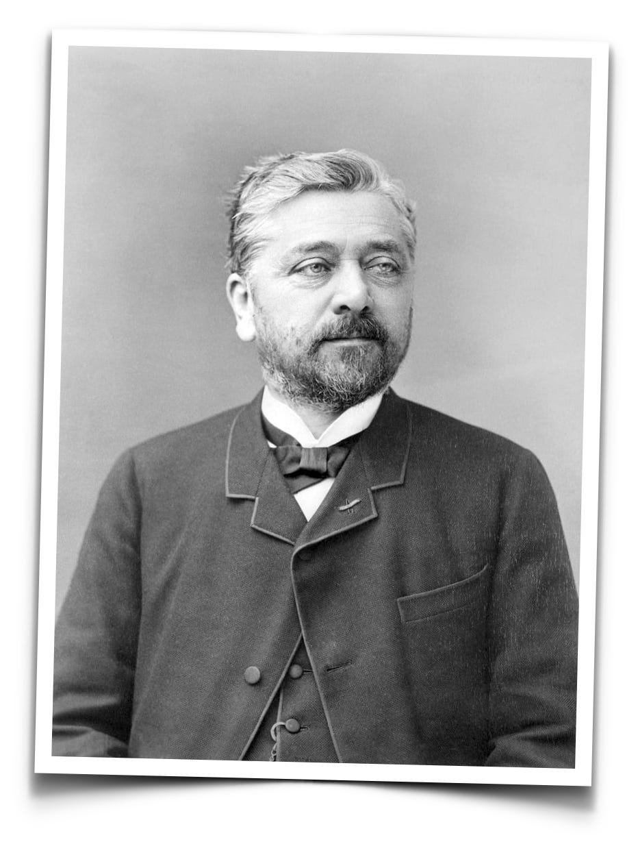 Black-and-white portrait of a bearded man in a suit with a bow tie, facing slightly to the right, against a plain background.