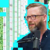 a man is standing in front of a wall of plants.