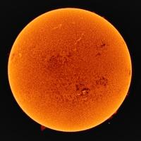 A close-up view of the Sun's surface, showcasing its bright, textured, orange appearance against a black background.