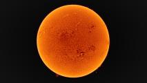 A close-up view of the Sun's surface, showcasing its bright, textured, orange appearance against a black background.